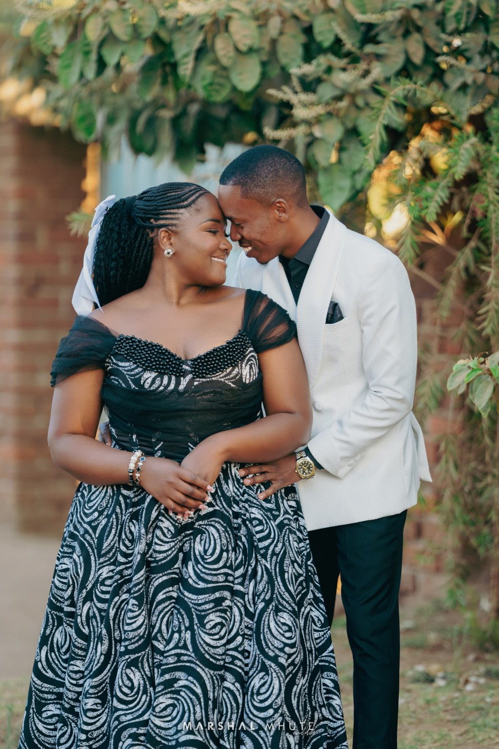 Couple smiling closely under trees