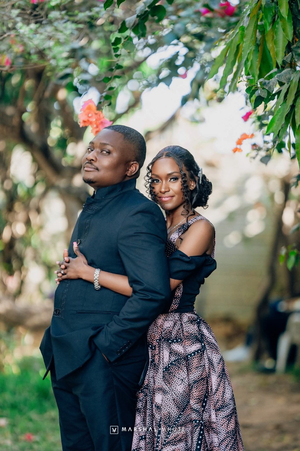 Couple in black formal outfits under trees