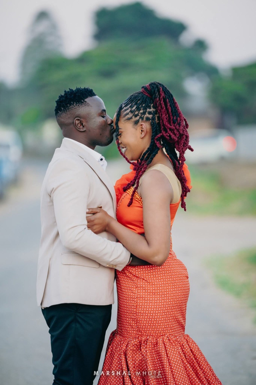 Couple sharing a forehead kiss in warm orange and cream tones